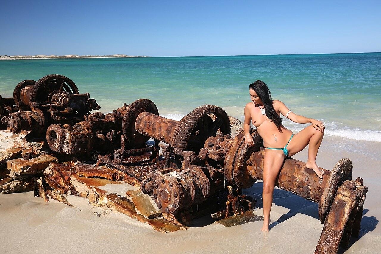 Brunette MILF Wild Thing goes topless while teasing in a bikini at the beach
